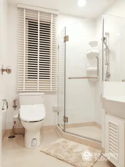 Pristine white bathroom with modern fixtures, glass shower enclosure, and elegant tiling, offering a serene and refreshing space in a contemporary home.