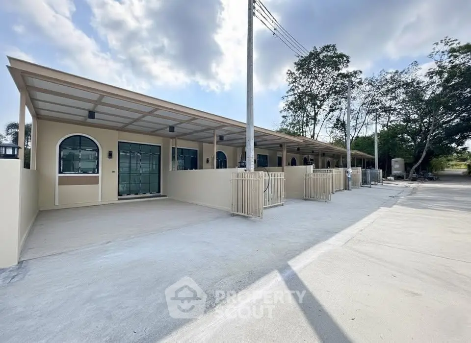 Modern row of beige townhouses with covered parking and lush greenery.