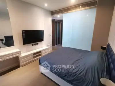 Modern bedroom with sleek built-in cabinets and entertainment unit, featuring a large bed with blue bedding and ambient lighting.