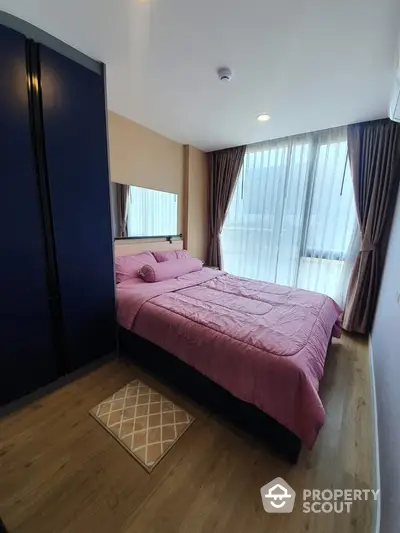 Cozy bedroom with pink bedding and large window for natural light