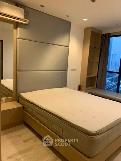 Modern bedroom with city view, featuring a comfortable bed and stylish decor.