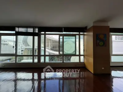 Spacious modern living room with large windows offering city views and elegant wooden flooring.