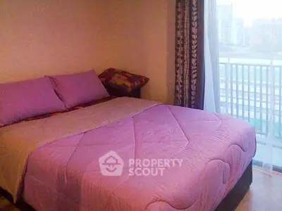 Cozy bedroom with purple bedding and city view from balcony.