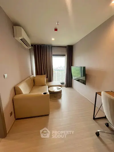 Modern living room with beige sofa, wall-mounted TV, and city view window.