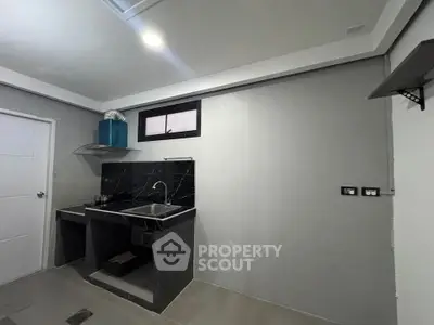 Modern minimalist kitchen with sleek black countertops and stainless steel sink.