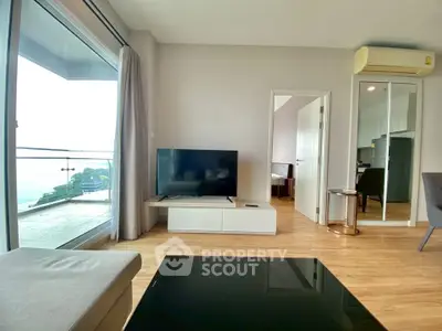 Modern living room with large window and balcony view, featuring sleek furniture and wooden flooring.