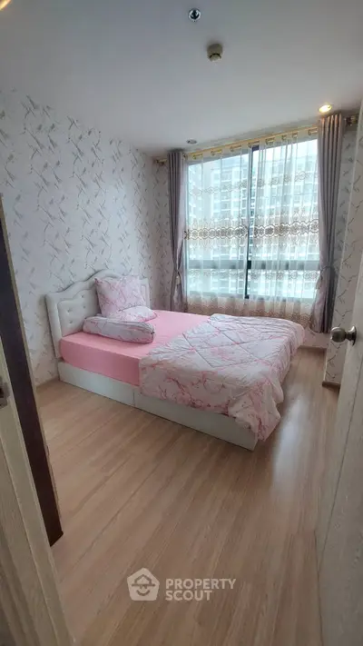 Cozy bedroom with pink bedding and large window in modern apartment
