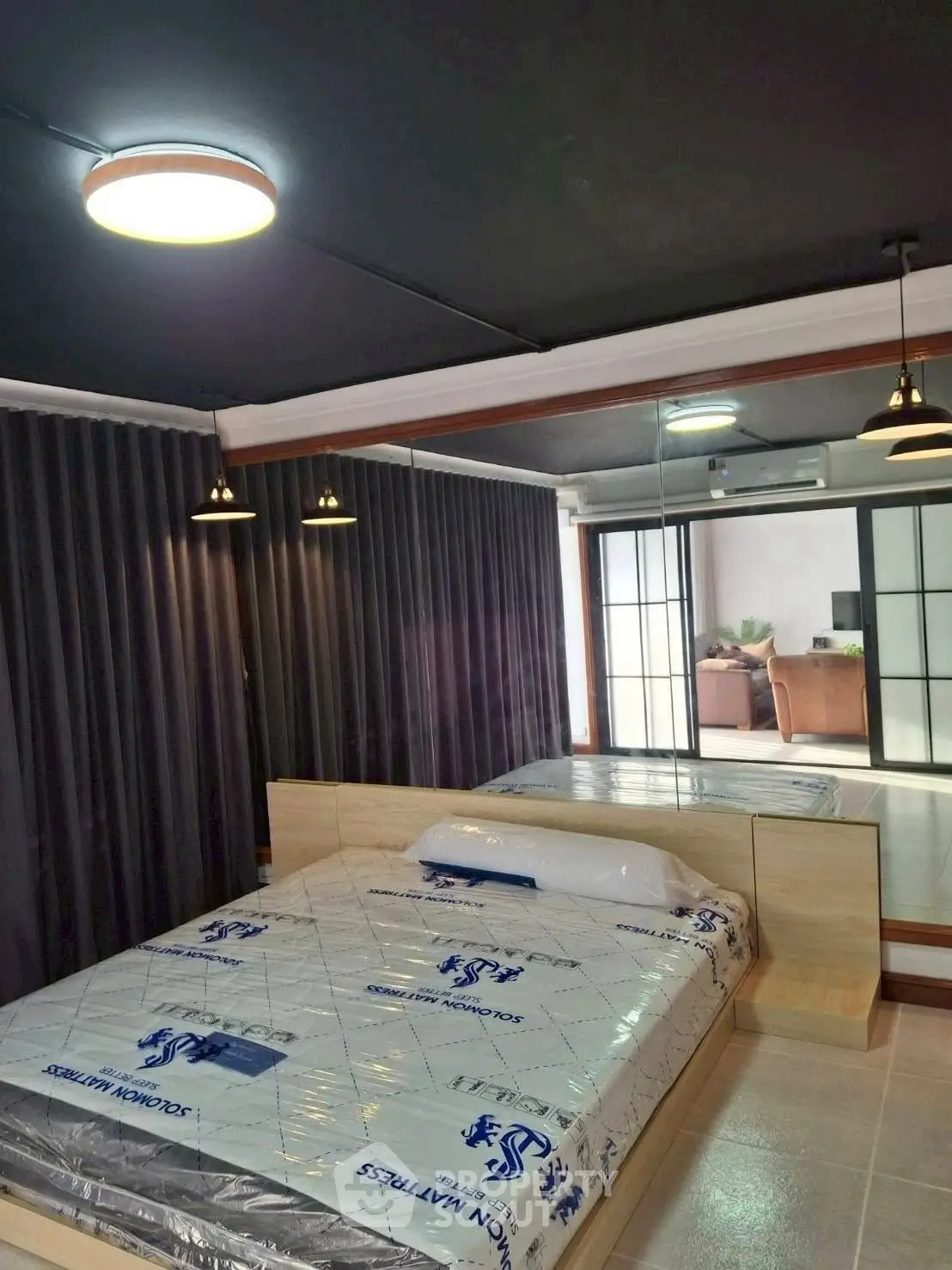 Modern bedroom with mirrored wall and stylish lighting in contemporary apartment.