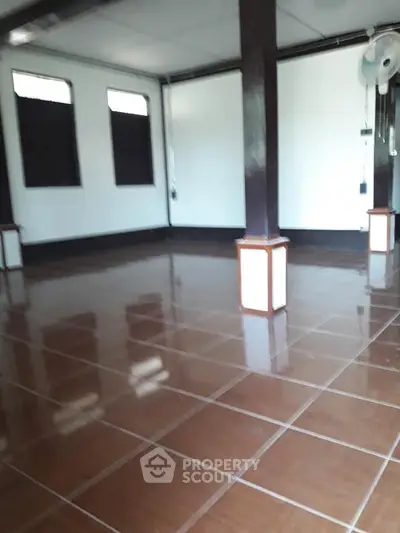 Spacious empty room with glossy tiled floor and dark wooden pillars, ideal for customization.