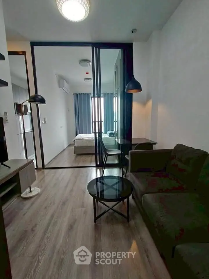 Modern apartment with open layout featuring a cozy living room and bedroom separated by glass doors.