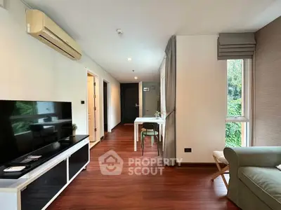 Modern living room with sleek furniture and large window offering natural light.