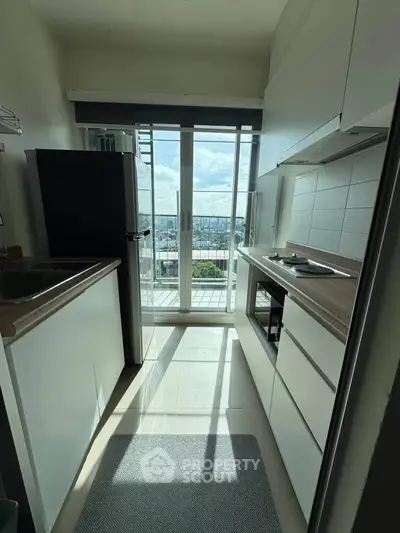 Modern kitchen with sleek cabinetry and city view from balcony, featuring a compact yet functional design.