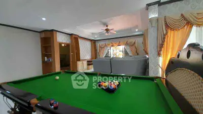 Spacious living room with pool table and elegant curtains
