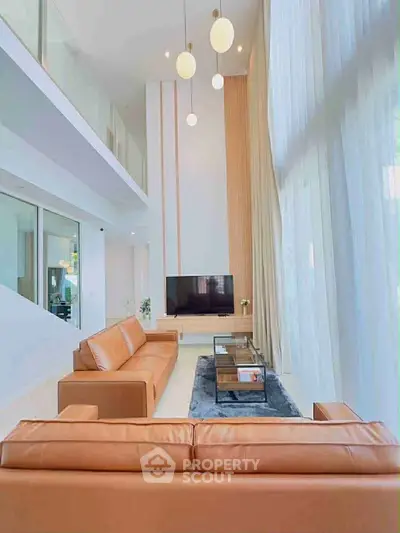 Luxurious high-ceiling living room with modern leather sofas and elegant decor