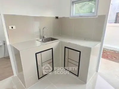 Modern kitchen with sleek cabinetry and stainless steel sink in a bright, minimalist design.