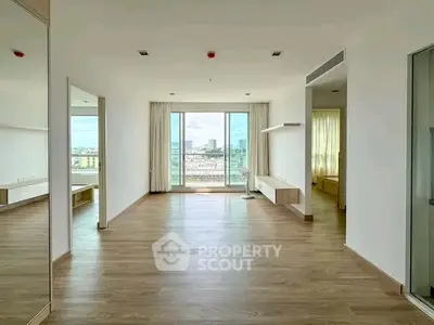 Spacious modern living room with large windows and city view, perfect for urban living.