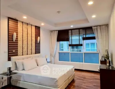 Spacious modern bedroom with elegant decor and large windows for natural light.