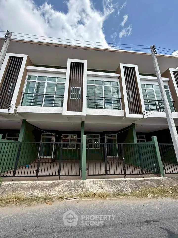 Modern townhouse exterior with large windows and gated entrance, perfect for urban living.