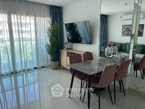 Modern living room with sleek decor, large TV, and natural light from balcony.