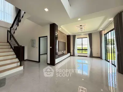 Spacious modern living room with large windows and elegant staircase