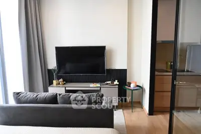 Modern living room with sleek TV setup and cozy sofa, adjacent to a stylish kitchen area.