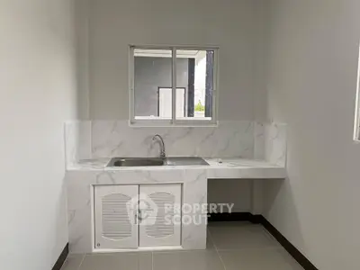 Minimalist kitchen with marble countertop and sink, bright and clean design.