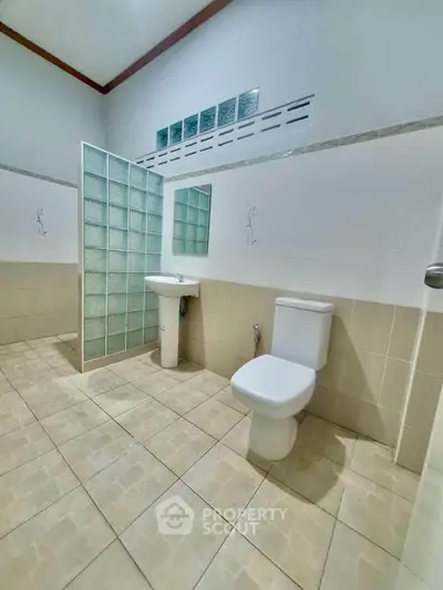 Spacious bathroom with modern fixtures and glass partition in a contemporary home.