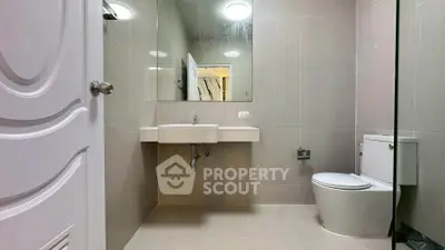 Modern bathroom with sleek fixtures and neutral tiles, featuring a large mirror and contemporary design.