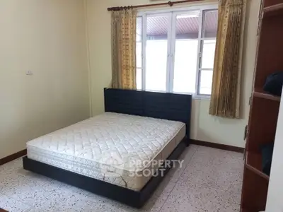 Cozy bedroom with large window and simple furnishings, perfect for a restful retreat.