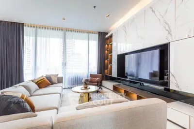 Luxurious modern living room with large TV and elegant marble wall, featuring plush sofas and floor-to-ceiling windows.