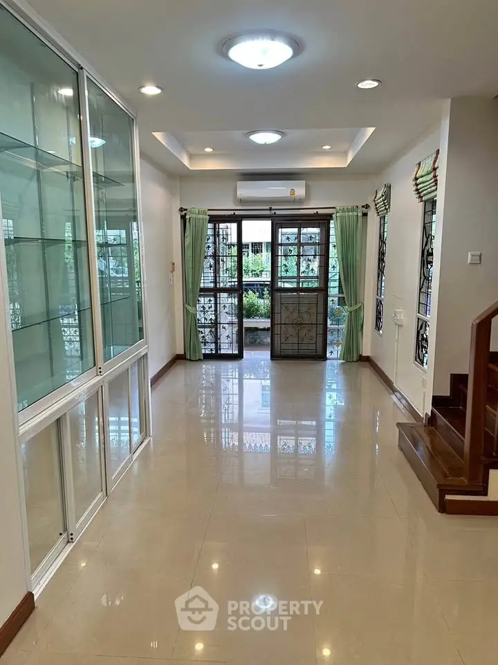 Spacious living room with glass cabinets and garden view, perfect for modern family living.