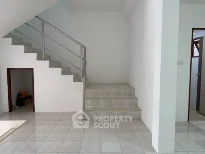 Spacious interior with modern staircase and tiled flooring, ideal for customization.