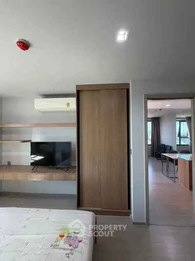 Modern bedroom with built-in wardrobe and wall-mounted TV in a stylish apartment.
