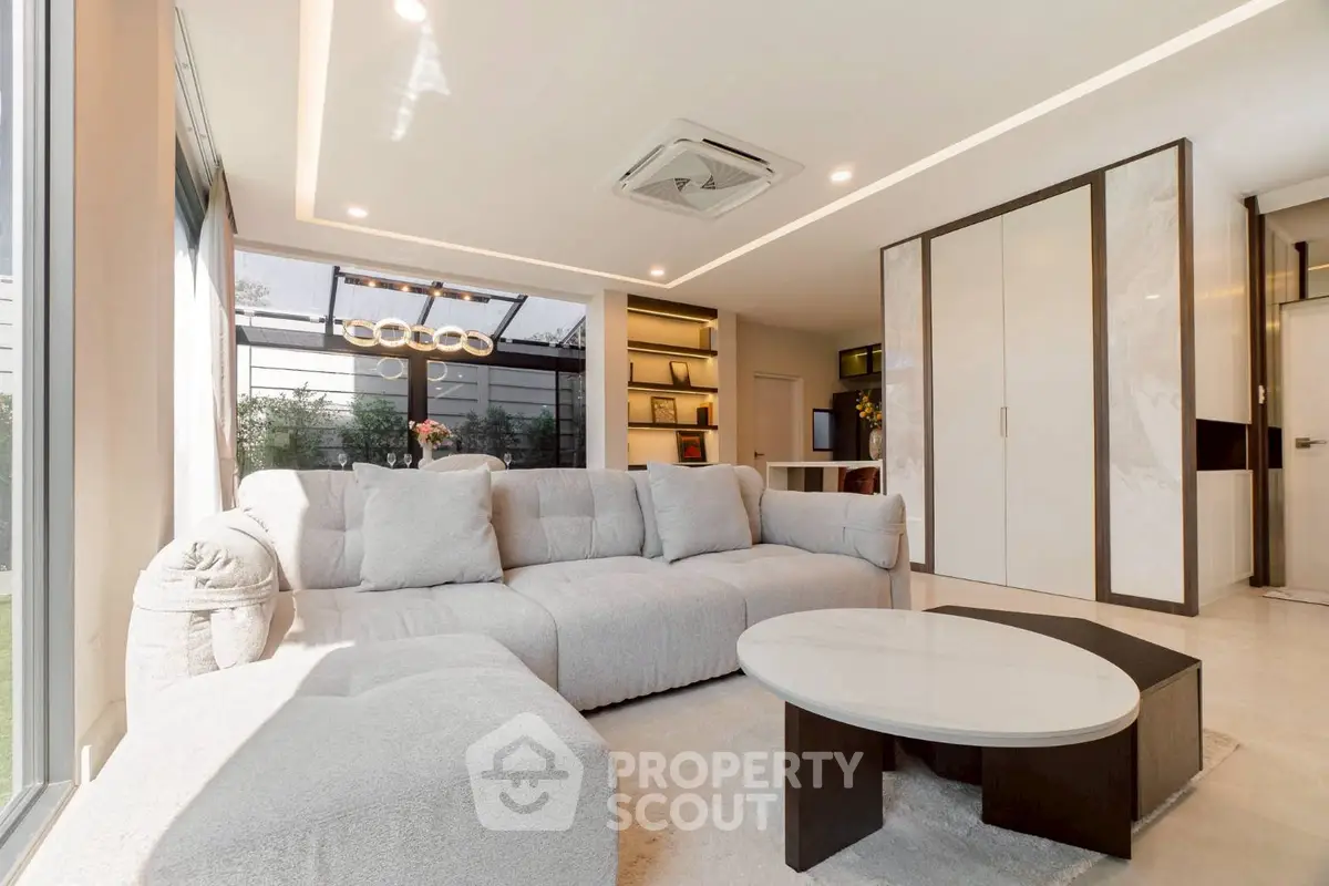 Modern living room with plush sofa and sleek decor, featuring large windows and ample natural light.