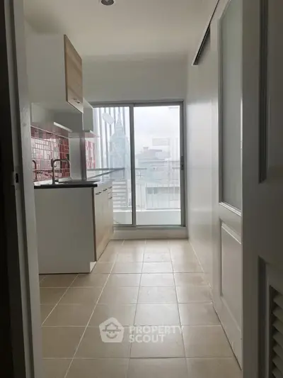 Modern kitchen with sleek cabinetry and city view from large window.