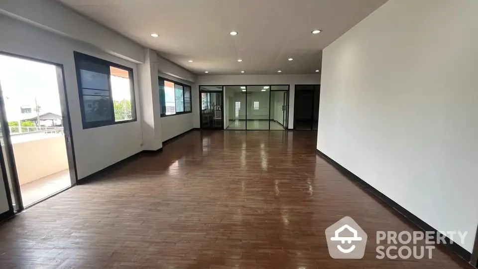 Spacious open-plan living area with wooden flooring and large windows