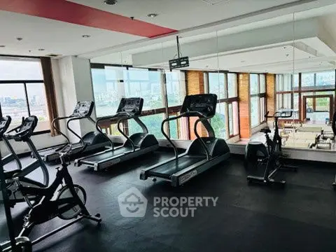 Spacious gym with modern equipment and panoramic city views, ideal for fitness enthusiasts.