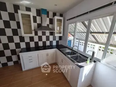 Modern kitchen with checkered backsplash and dual sink, featuring a gas stove and ample natural light.