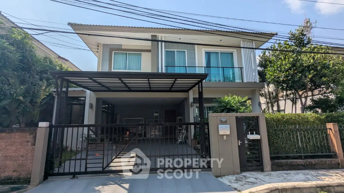 Modern two-story house with gated entrance and carport in a suburban neighborhood.