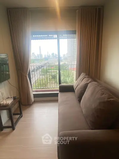 Cozy living room with a stunning city view from a large window, featuring a comfortable sofa and modern decor.
