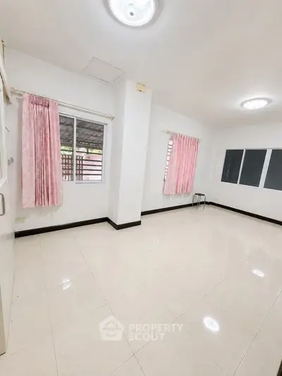 Spacious empty room with tiled floor and pink curtains, ideal for customization.