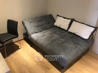Cozy bedroom with modern gray futon and wooden flooring