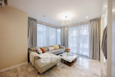 Elegant living room with chandelier, cozy sectional sofa, and large windows for natural light.