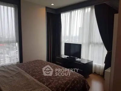 Cozy bedroom with large windows and modern decor in a high-rise apartment.