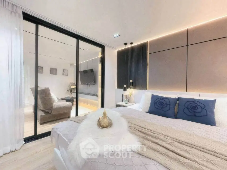 Luxurious modern bedroom with elegant decor and sliding glass doors leading to a cozy living area.
