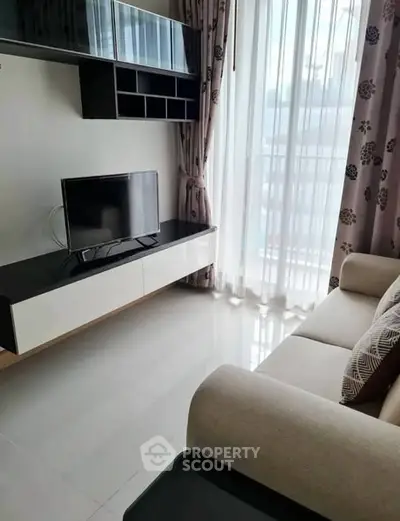 Modern living room with sleek TV setup and large window for natural light.