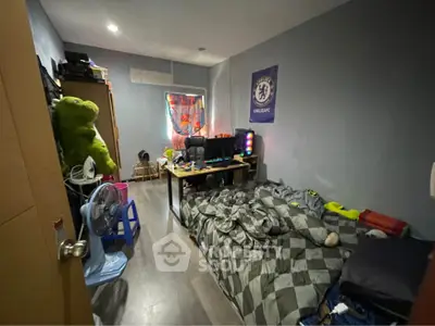 Cozy bedroom with modern decor and gaming setup, perfect for relaxation and entertainment.