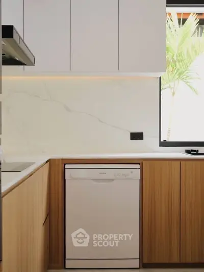 Modern kitchen with sleek cabinetry and integrated dishwasher, featuring a minimalist design and natural light.