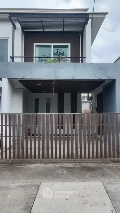 Modern two-story house with balcony and gated entrance