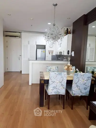 Chic dining area with floral chairs and modern kitchen in open layout apartment.